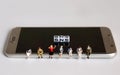 A variety of miniature people sitting and `SNS` text white cube on Smart phone.