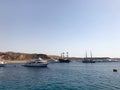 A variety of motor and sailing ships, boats, cruise liners stand on a dock in the port against the background of the blue sea and