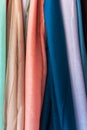 Variety of multicolored fine organic cotton scarves of pastel colors hanging at store display market. Elegant feminine style