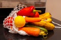 Variety of organic fruits and vegetables in avoska on the kitchen table. Banana, lemon, carrot, cucumber and pepper in string bag