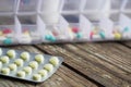 Variety of pills in white plastic pill organizer on weathered wood Royalty Free Stock Photo