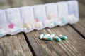 Variety of pills in white plastic pill organizer on weathered wood Royalty Free Stock Photo