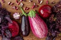 Variety of purple veggies and basil on wooden table. Flat lay, overhead. Close up