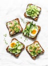 Variety sandwiches with cream cheese, egg, asparagus, avocado, cucumber, shrimp, micro greens on a light background, top view.