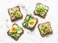 Variety sandwiches with cream cheese, egg, asparagus, avocado, cucumber, shrimp, salami, micro greens on a light background, top