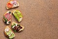 A variety of sandwiches with red fish, smoked sausage, vegetable on a brown stone background. Top view, copy space Royalty Free Stock Photo