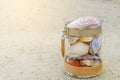 Variety of sea shells in glass jar on the sand beach with copy space. holiday concept Royalty Free Stock Photo