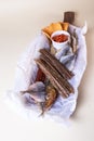 A variety of smoked fish on a wooden board with a bowl of red pepper flakes. assorted fish