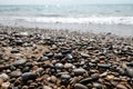 Variety of smooth pebbles, rocks and stones at seashore. Quiet peaceful beach with water waves coming in. Escaping to dream Royalty Free Stock Photo