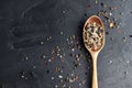 Variety of spices in wooden spoon. Sea salt, mixed pepper, cardamon and mustard seeds on dark black slate background. Royalty Free Stock Photo