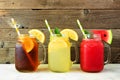 Iced tea, lemonade and watermelon juice summer drinks in mason jar glasses against dark wood