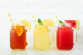 Iced tea, lemonade and watermelon juice summer drinks in mason jar glasses against white wood