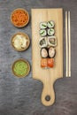 Variety of sushi on cutting board. Pickled ginger and carrots, wasabi in wooden bowls Royalty Free Stock Photo