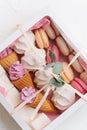 Variety of sweets in a box laid in vertical rows in a white windowed tied box