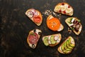 A variety of toast with vegetables, fruits, salmon and sausage on a dark background, top view. Sandwiches with a variety of