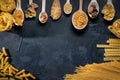 Variety of types and shapes of Italian pasta in wooden spoons. Dry pasta background. Italian food concept Royalty Free Stock Photo