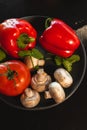 Variety of vegetables. Bell pepper, tomato and champignon on dark plate.