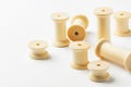 Variety of wooden thread spools reels of different sizes scattered on white background. Sewing crafts hobbies tailoring fashion