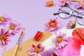 Various art and stationary supplies: glasses, brushes, watercolors, colored flowers and other accessories.