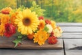 Various autumn flowers on a wooden table. Forest in the background. Royalty Free Stock Photo