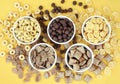 Various breakfast cereals on yellow bright background, assorted corn flakes in bowls