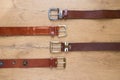 Collection of various brown leather belts on a wooden board