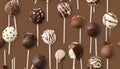 Various cake pops decorated with white and dark chocolate on a brown background