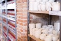 Various clay mugs and cups on racks in pottery shop