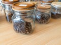 Various Coffee Bean On The Close Bottle Glass Jar With Wooden Lid at Wooden Table