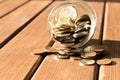 Various coins are scattered on a wooden table. The concept of poverty