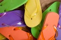 Various colored flipflops on sand