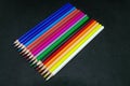 Various colored pencils neatly arranged in parallel against black background. Royalty Free Stock Photo