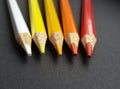 Colored pencils over black background. Warm colors. White, yellow, orange and red. Royalty Free Stock Photo