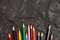 Various colored wooden pencils on black carbon paper background Royalty Free Stock Photo