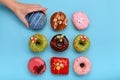 Various colorful donuts on blue background, female hand takes a donut. Top view. Royalty Free Stock Photo