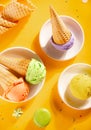 Various colorful ice cream scoops or balls with waffle cones on yellow background. Top view Royalty Free Stock Photo