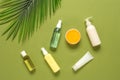 Various cosmetic products for face and body on a green olive textured paper background with artificial palm leaves. Top Royalty Free Stock Photo