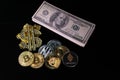 Various crypto coins lie next to a stack of 100-dollar bills, a white alarm clock and a diamond-studded dollar chain pendant Royalty Free Stock Photo