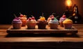 Various cupcakes sitting on a board in the kitchen.