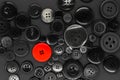 Various dark clothes buttons background with one red button Royalty Free Stock Photo