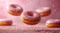 Various decorated donuts in motion falling on pink background.