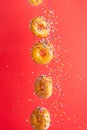 Various decorated donuts in motion falling on a red background. Sweet and iced donuts fall or fly in motion. With caramel. Royalty Free Stock Photo