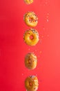 Various decorated donuts in motion falling on a red background. Sweet and iced donuts fall or fly in motion. With caramel. Royalty Free Stock Photo