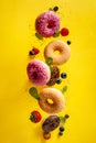 Various decorated doughnuts with sprinkles and berries in motion falling on yelloy background Royalty Free Stock Photo