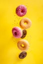 Various decorated doughnuts with sprinkles in motion falling on yelloy background Royalty Free Stock Photo