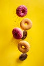 Various decorated doughnuts with sprinkles in motion falling on yelloy background Royalty Free Stock Photo