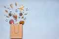 Various decorative nautical items, seashells, sea stars and miniature toys flying from kraft paper bag on blue pastel background.