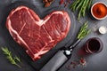 Various degrees of doneness of heart-shaped beef steak with spices, flowers and a bottle of wine on a stone dark