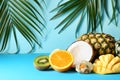 Various delicious exotic fruits with tropical leaves on color background