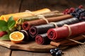 Various delicious fruit leather rolls on wooden table. Generate ai